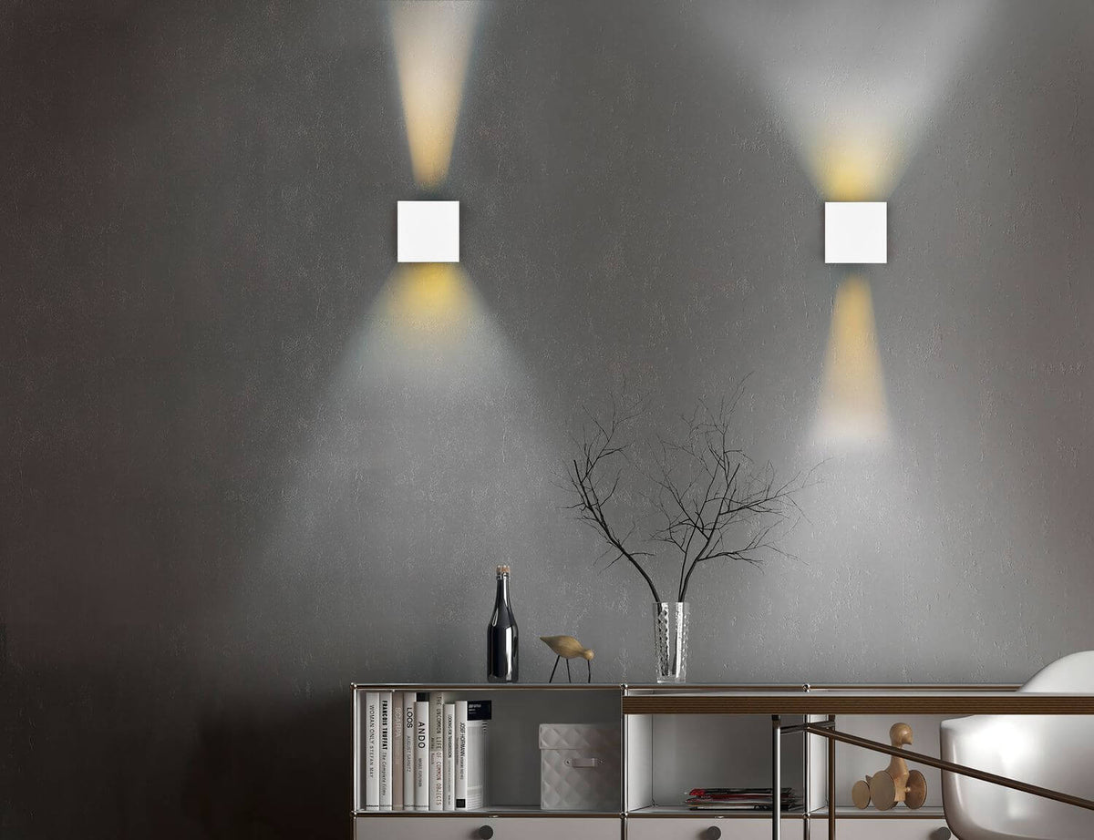 Mise en ambiance sur mur gris : deux appliques projetant des faisceaux haut et bas