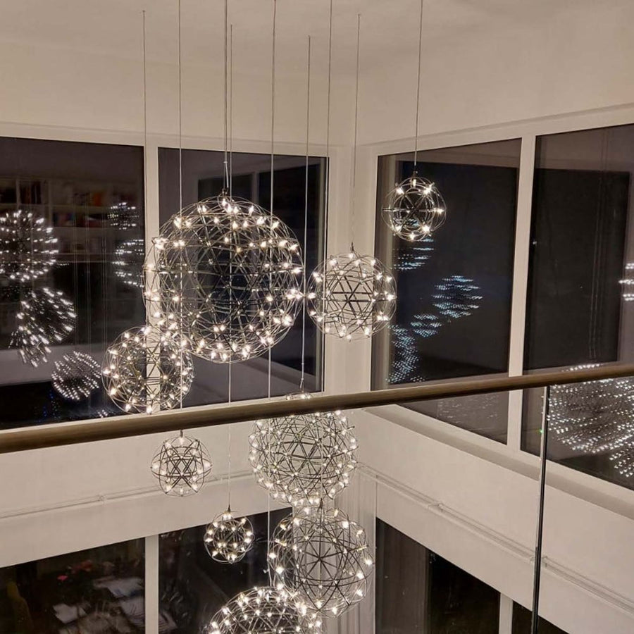 Nombreuses sphères lumineuses suspendues dans une cage d'escalier aux larges baies vitrées
