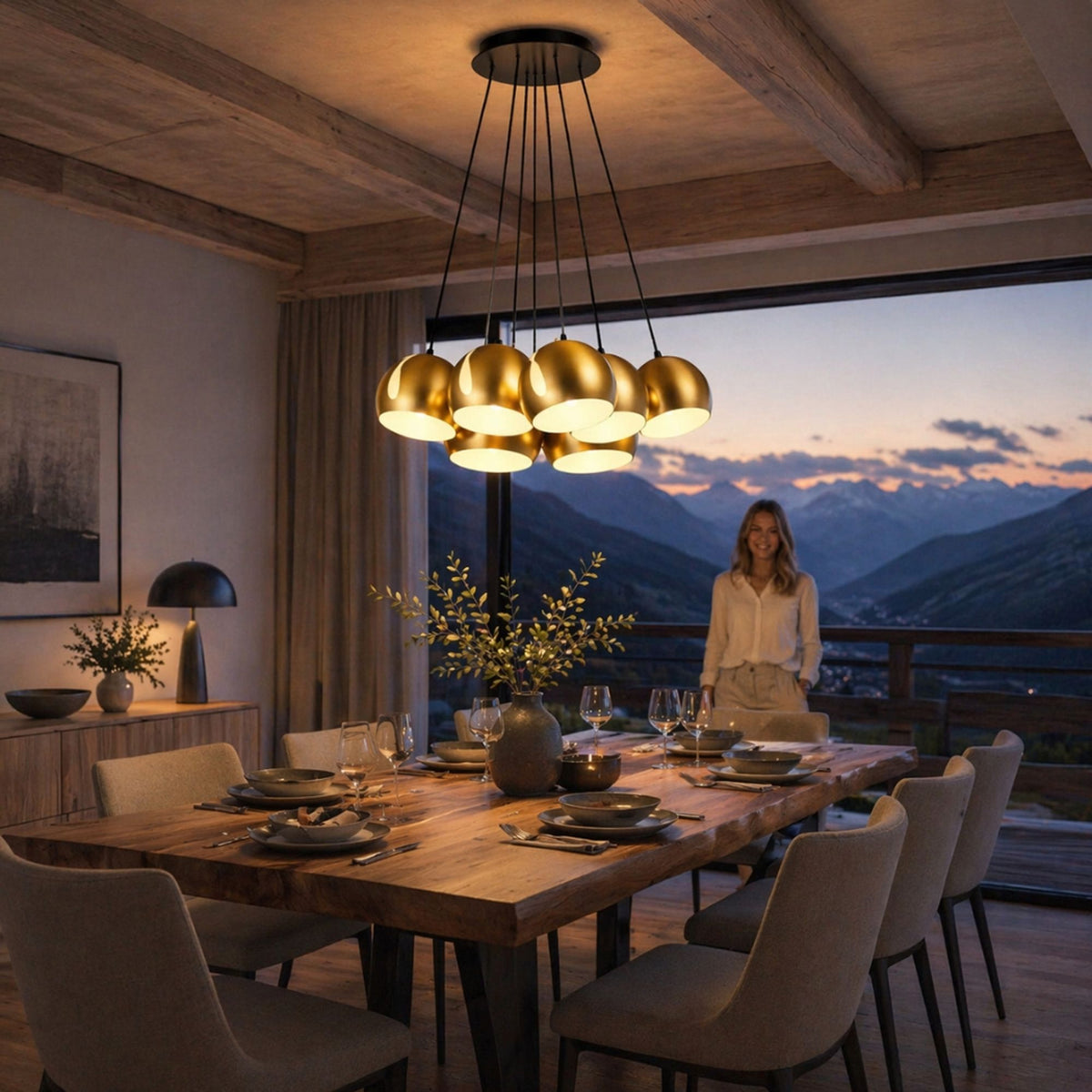 Suspension dorée à sept globes allumée au-dessus d'une table en bois, vue sur montagnes