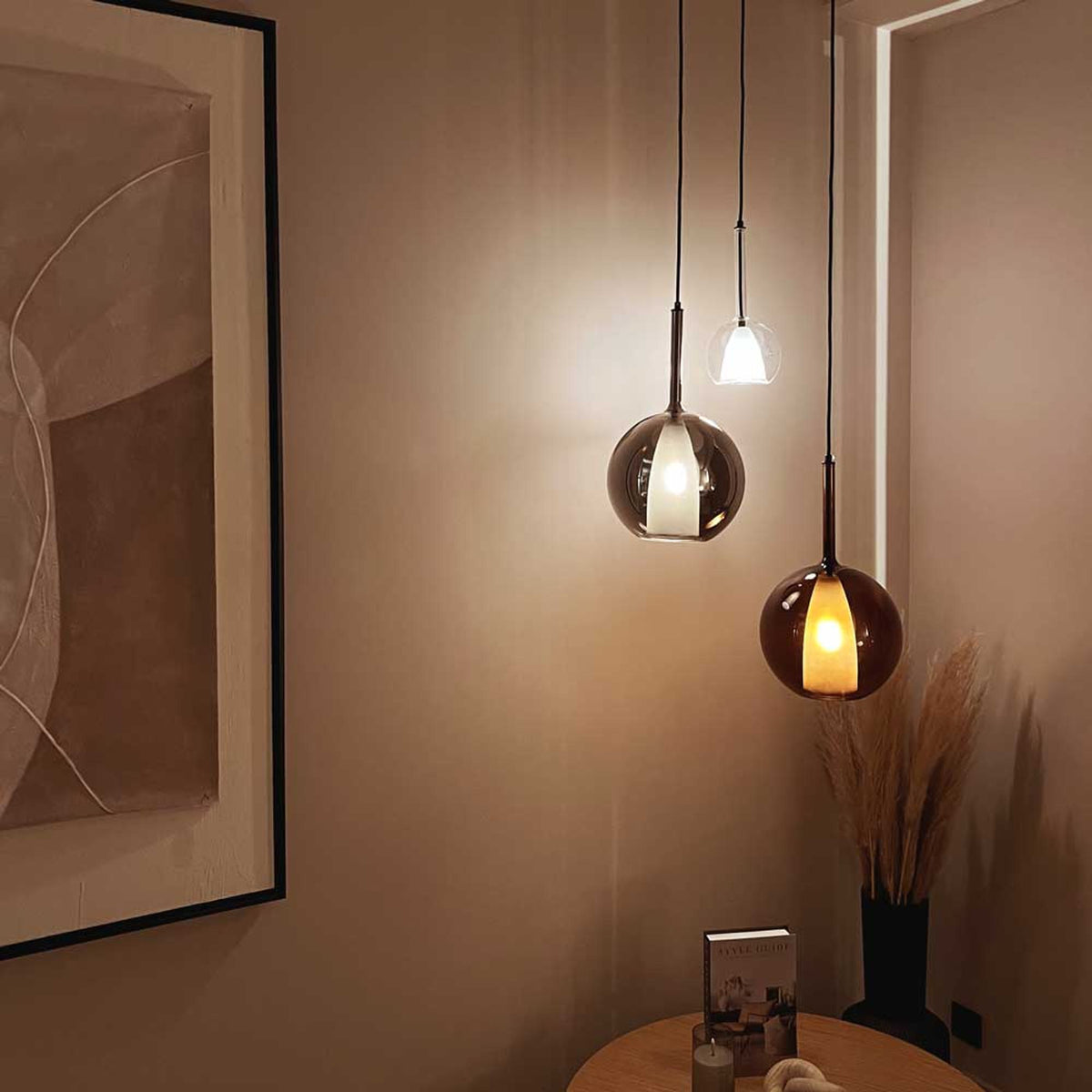 Trois globes suspendus devant un mur beige, ambiance chaleureuse en soirée
