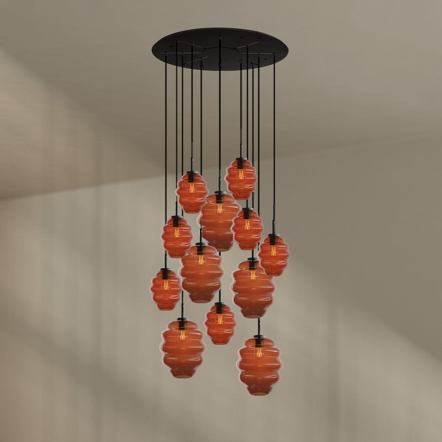 Gros plan de la suspension douze lumières aux verres ambrés godronnés sur fond beige clair