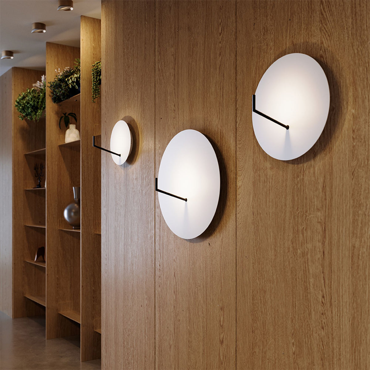 Trois appliques rondes blanches de tailles différentes sur cloison bois, ambiance chaleureuse.