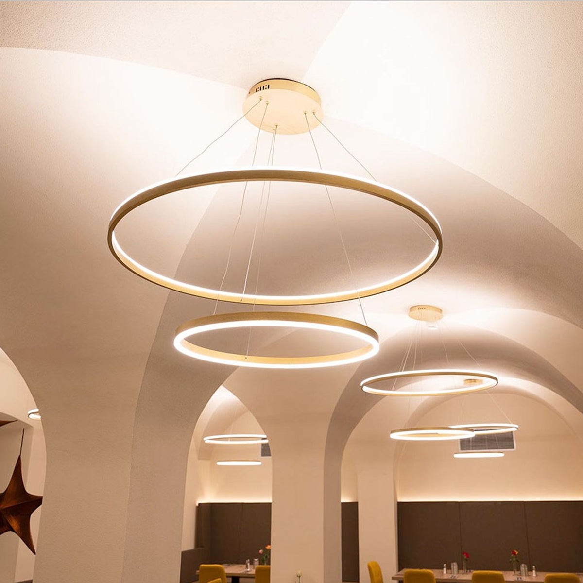 Suspension double anneaux dorés vue de dessous sous voûtes blanches éclairées