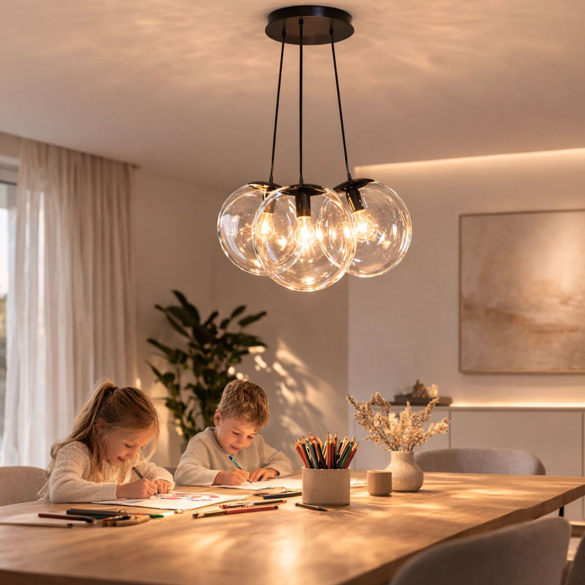 Luminaire suspendu à trois globes transparents éclairant des enfants qui dessinent