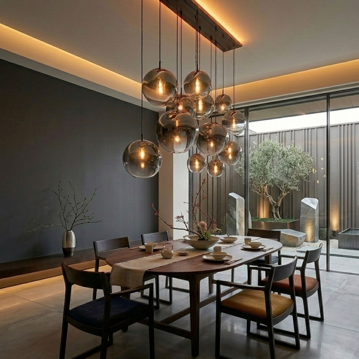 Globes en verre fumé suspendus au-dessus d'une table ovale en bois foncé.