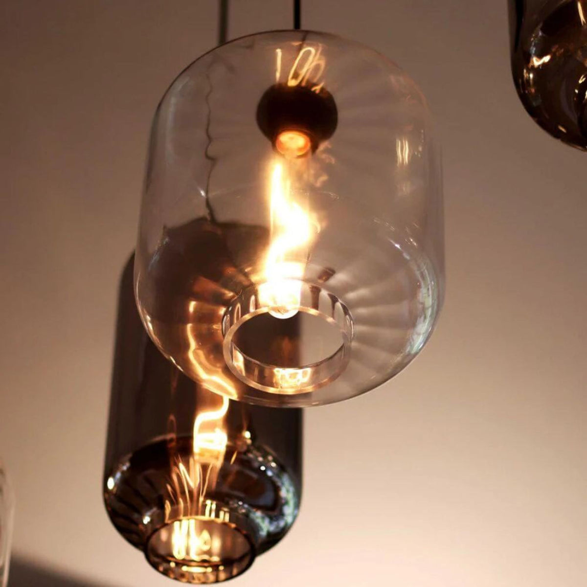 Gros plan sur la base cerclée d'un verre transparent, reflets chauds de l'ampoule