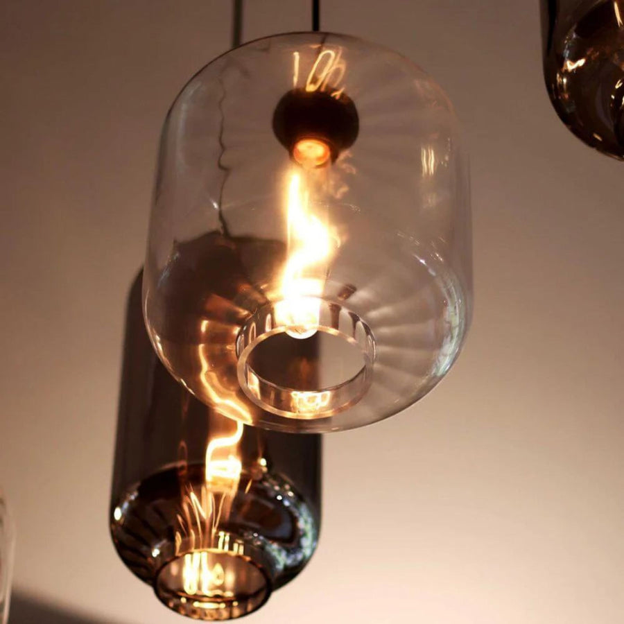 Gros plan sur la base cerclée d'un verre transparent, reflets chauds de l'ampoule
