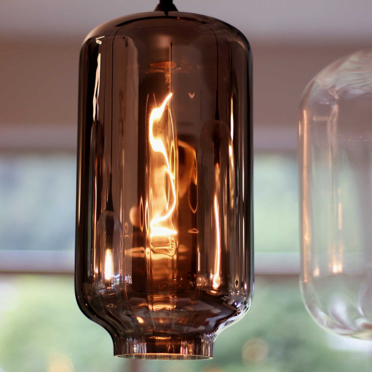 Détail macro d'un verre fumé avec ampoule à filament allumée à l'intérieur