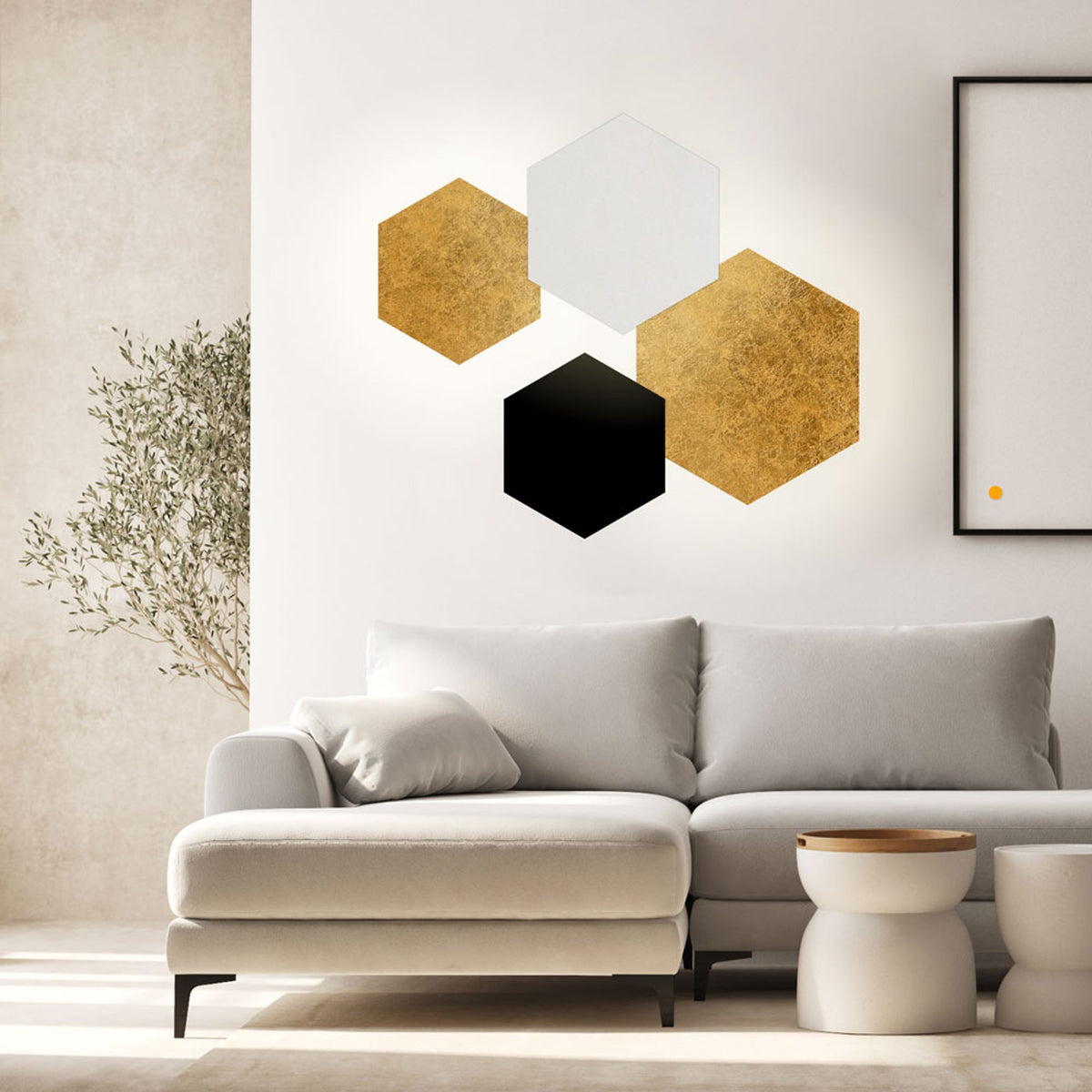 Composition murale de plusieurs hexagones dorés, blanc et noir au-dessus d'un canapé gris clair.
