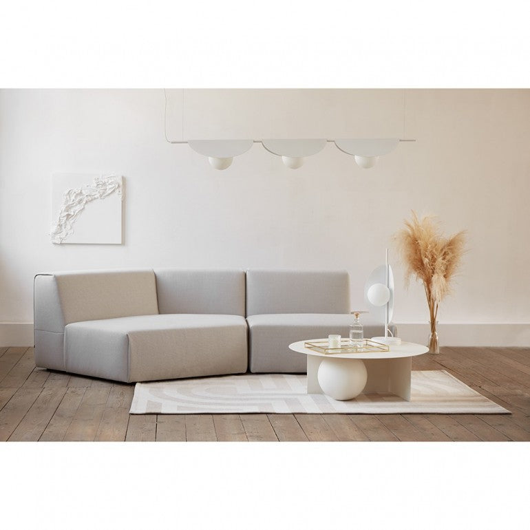 Mise en ambiance salon clair, suspension blanche au-dessus d'un canapé d'angle