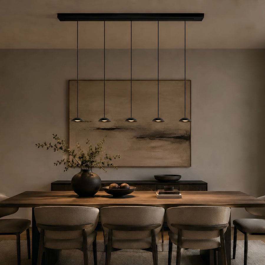 Suspension noire à cinq lumières alignées au-dessus d'une table à manger