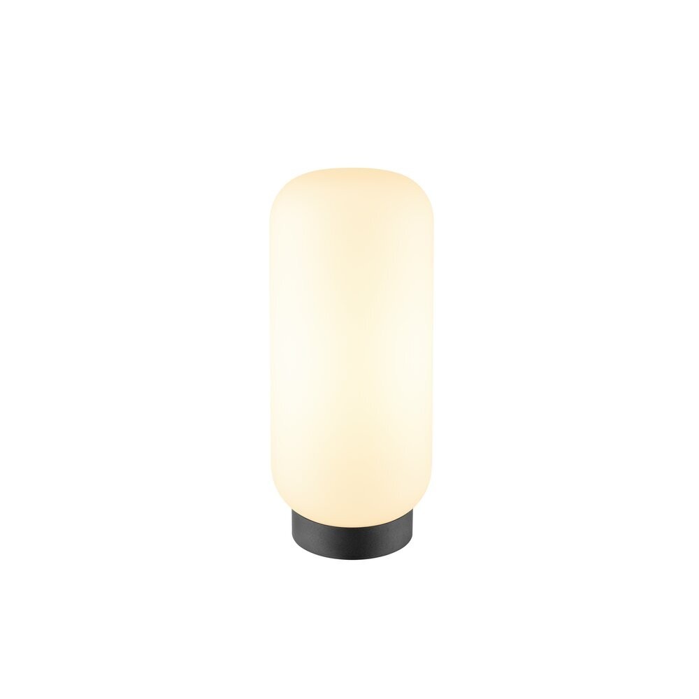 Lampe à poser blanche allumée, silhouette cylindrique arrondie sur socle noir.