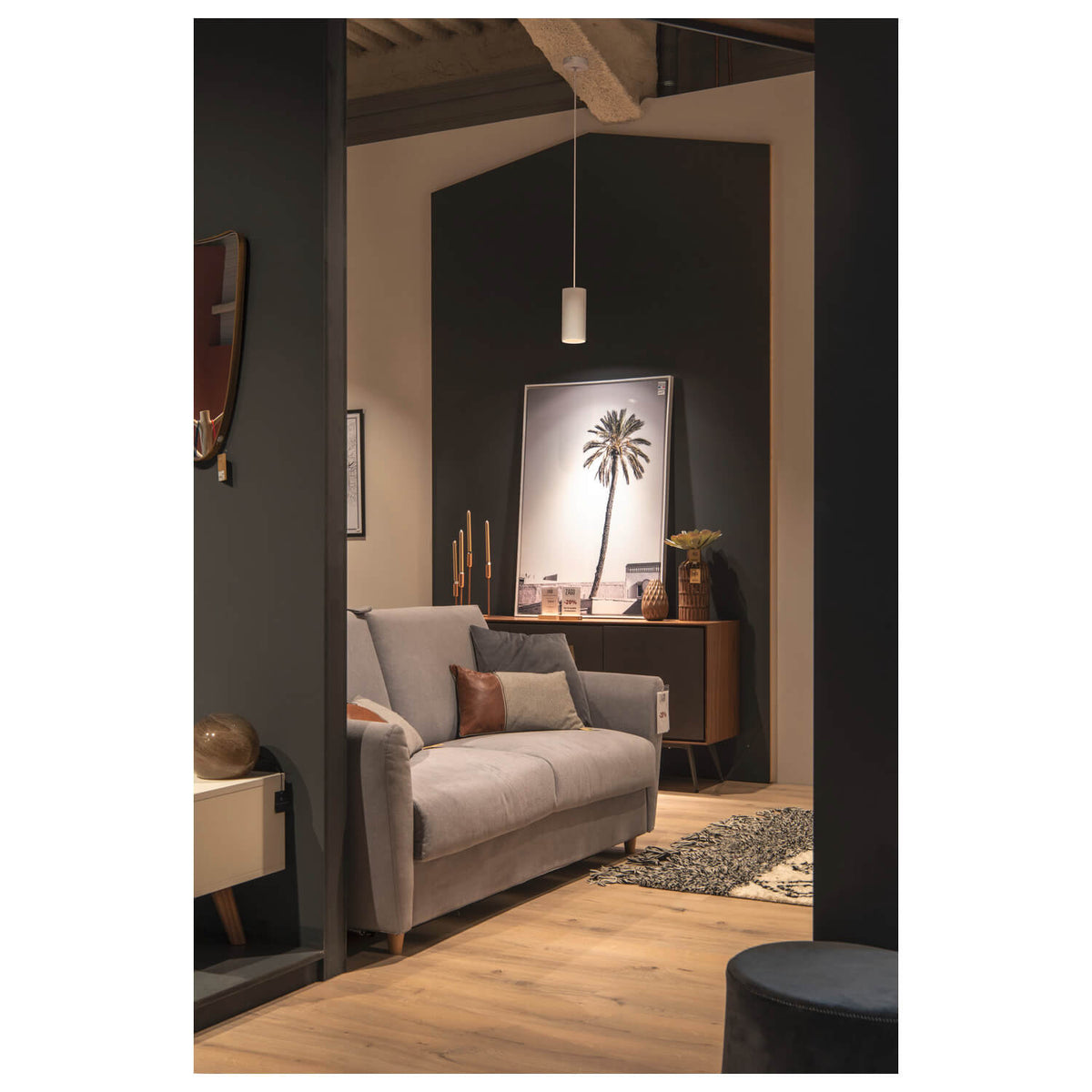 Mise en ambiance dans un salon sombre, suspension allumée au-dessus du canapé.