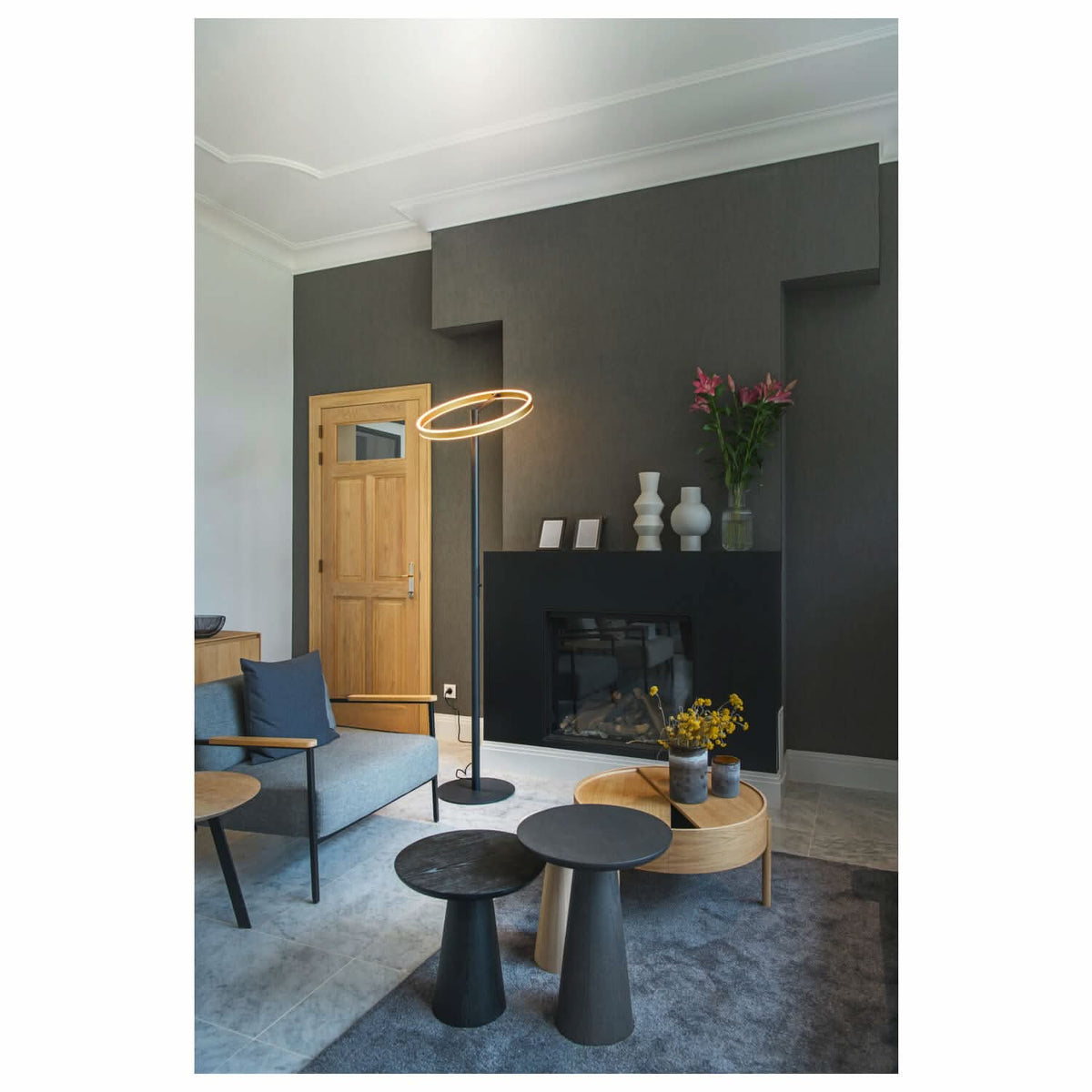 Mise en ambiance du lampadaire dans un salon sombre, près de la cheminée et du canapé.