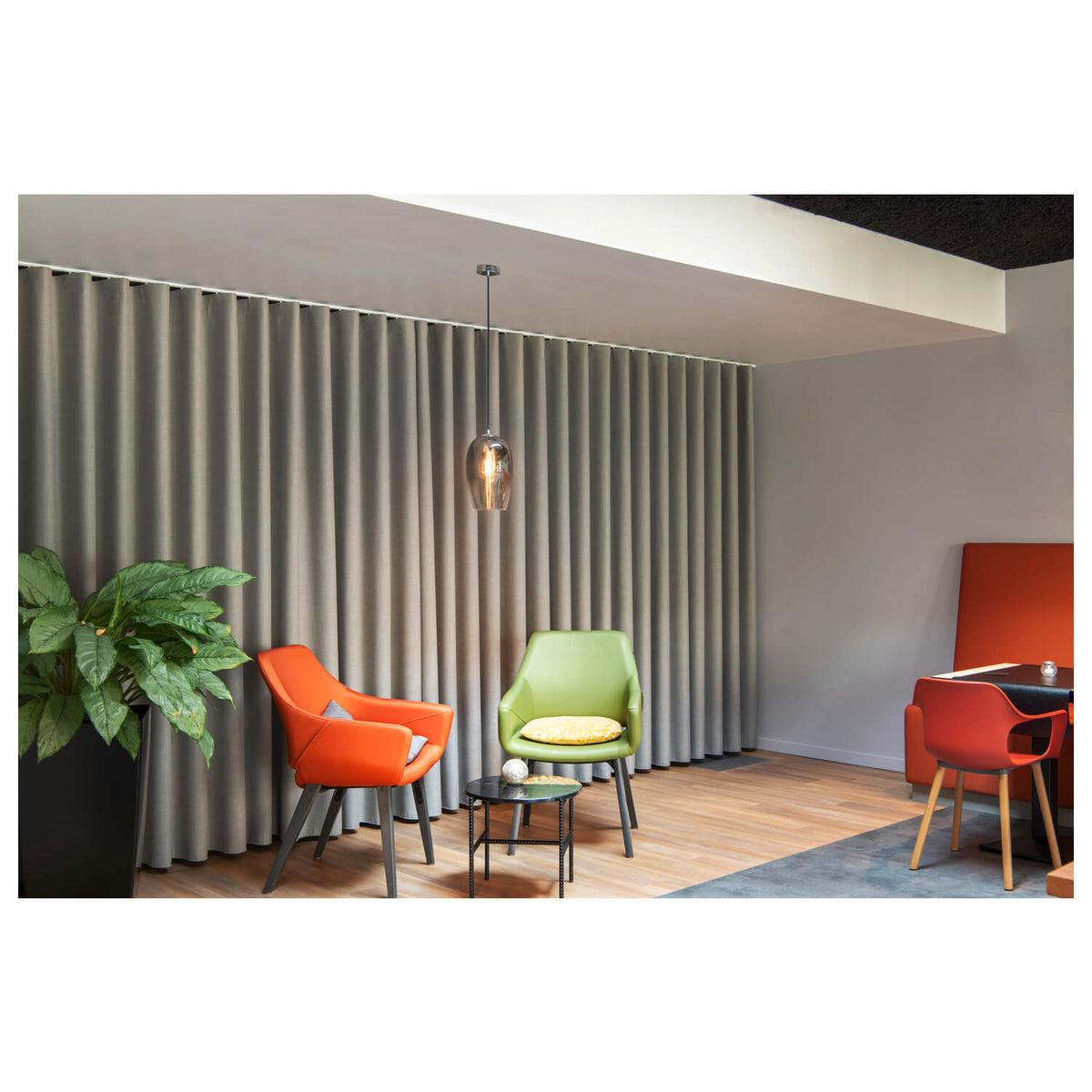 Mise en ambiance de la suspension dans un salon moderne avec fauteuils colorés