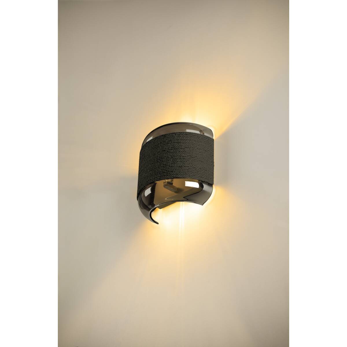 Applique allumée sur mur beige diffusant un halo lumineux vers le haut et le bas