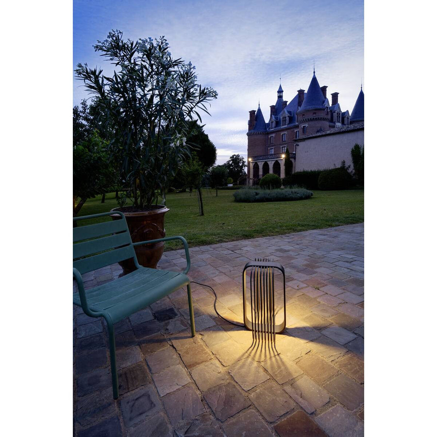 Luminaire extérieur éclairant une terrasse en pierre devant un château