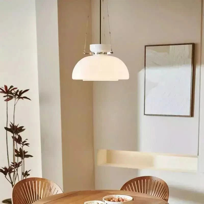 Suspension design au-dessus d'une table en bois, dans une salle à manger lumineuse.