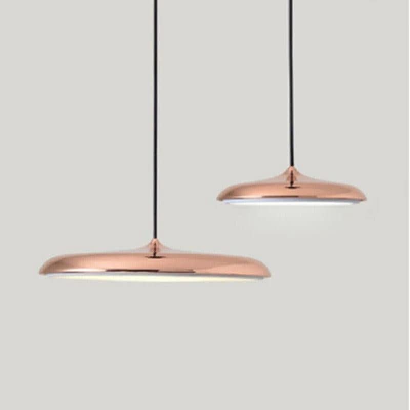 Deux suspensions cuivrées brillantes au design ovni sur fond gris.