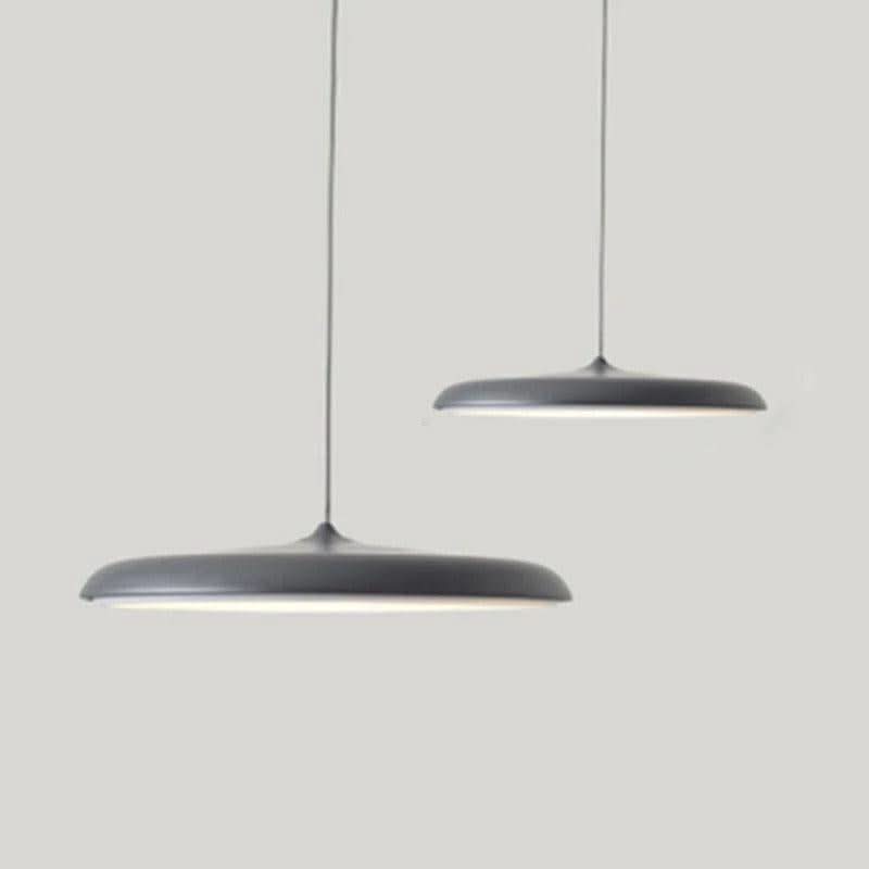 Deux suspensions noires de forme ovni suspendues sur fond gris clair.