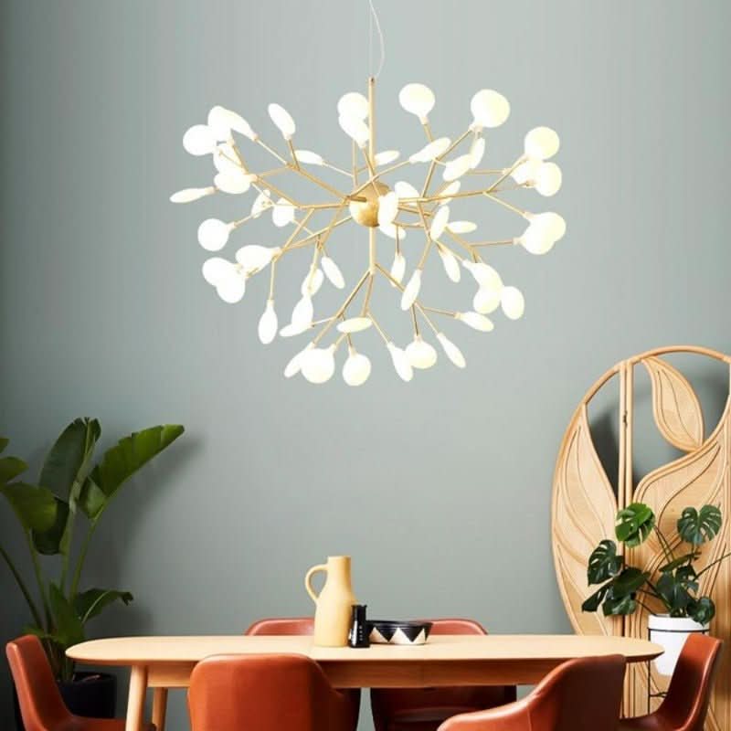 Version dorée au-dessus d'une table, branches fines et diffuseurs blancs ovales.