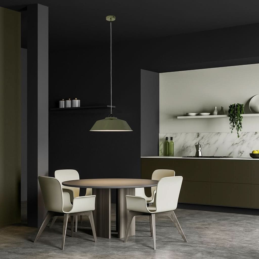 Suspension verte suspendue au-dessus d'une table ronde dans une cuisine sombre, ambiance chaleureuse.