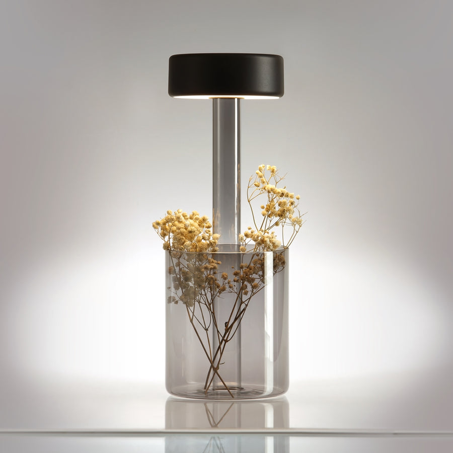 Lampe de chevet avec base en verre fumé contenant des fleurs séchées, produit en situation.