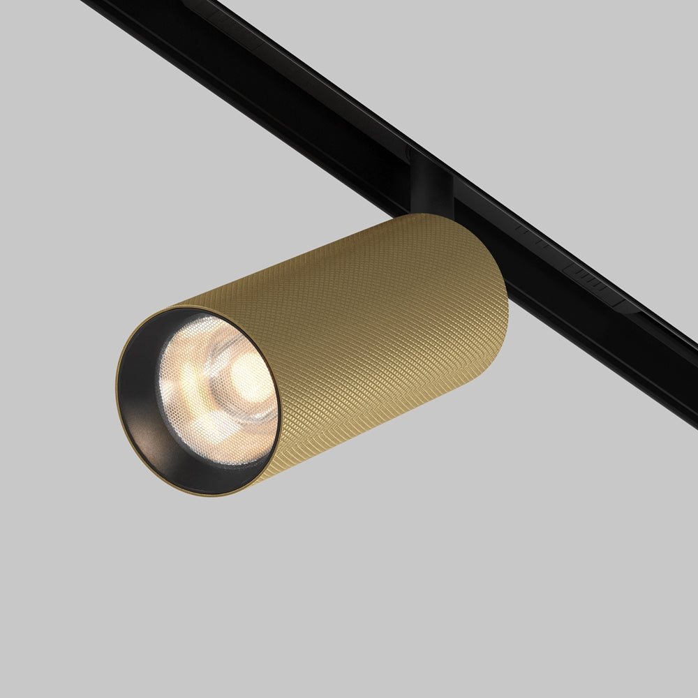 Spot cylindrique doré fixé sur rail noir, vue de trois quarts face