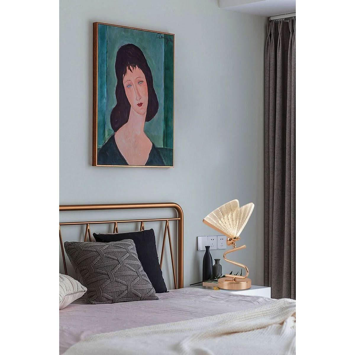 Lampe de chevet en laiton doré près d'un lit sous un tableau encadré