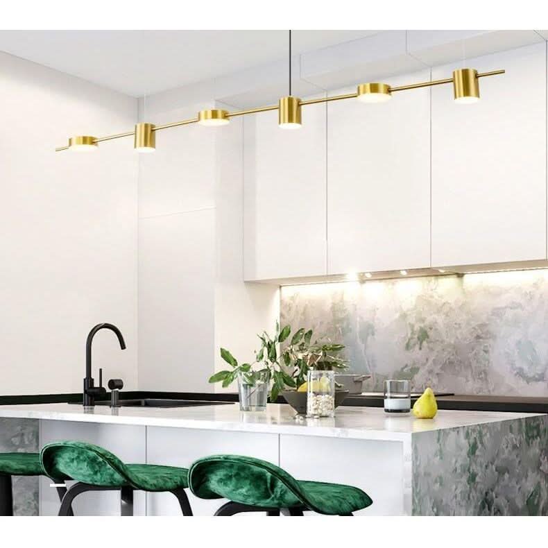 Suspension laiton à cinq cylindres éclairant un îlot blanc et tabourets verts