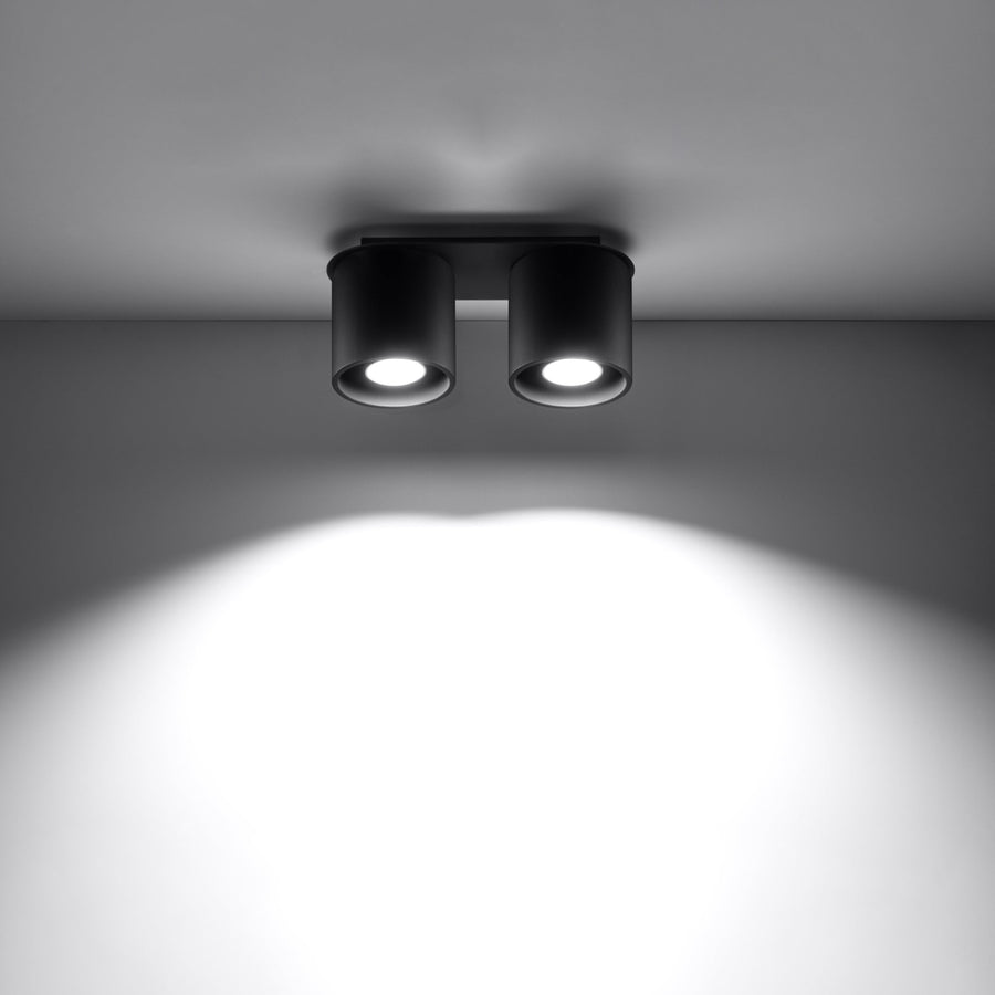 Plafonnier noir allumé fixé au plafond, éclairant une pièce sombre.