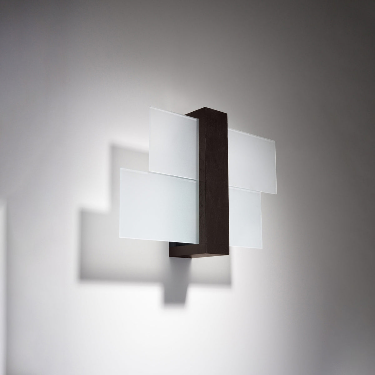 Applique allumée sur mur blanc, halo lumineux et ombres douces projetées