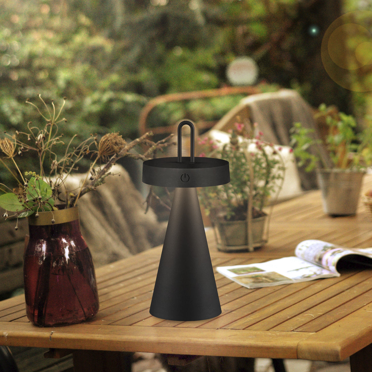 Mise en ambiance sur table en bois avec plantes, vase et magazine.
