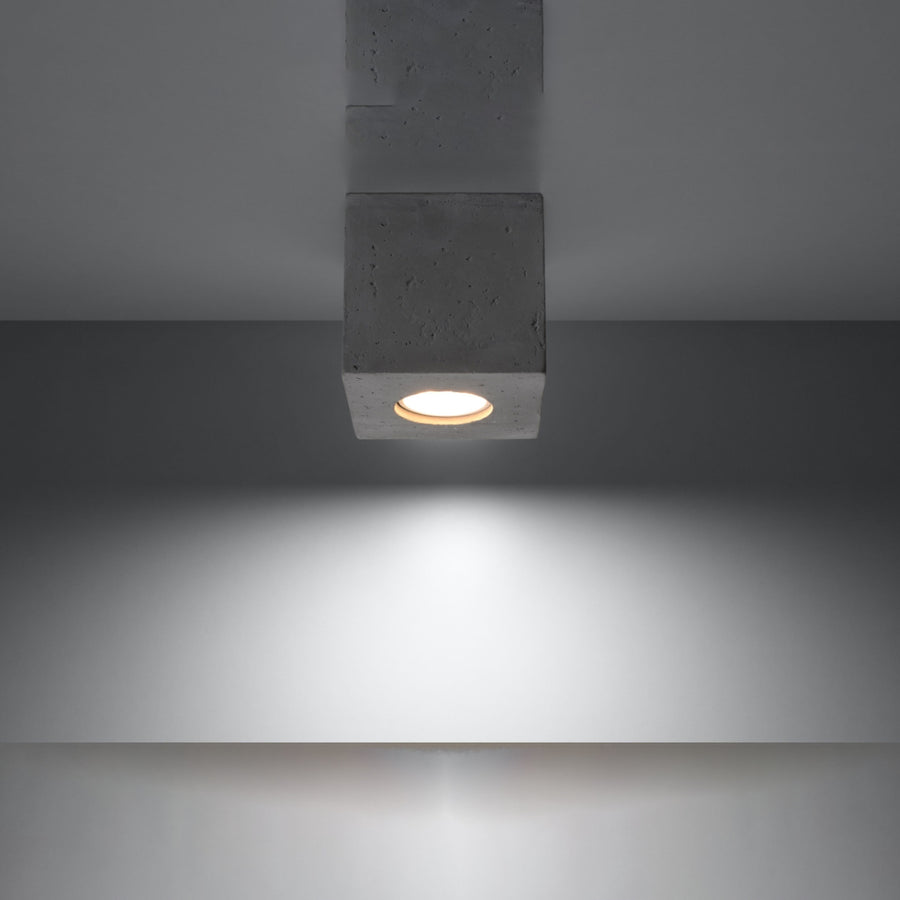 Luminaire allumé fixé au plafond projetant un halo lumineux vers le bas.