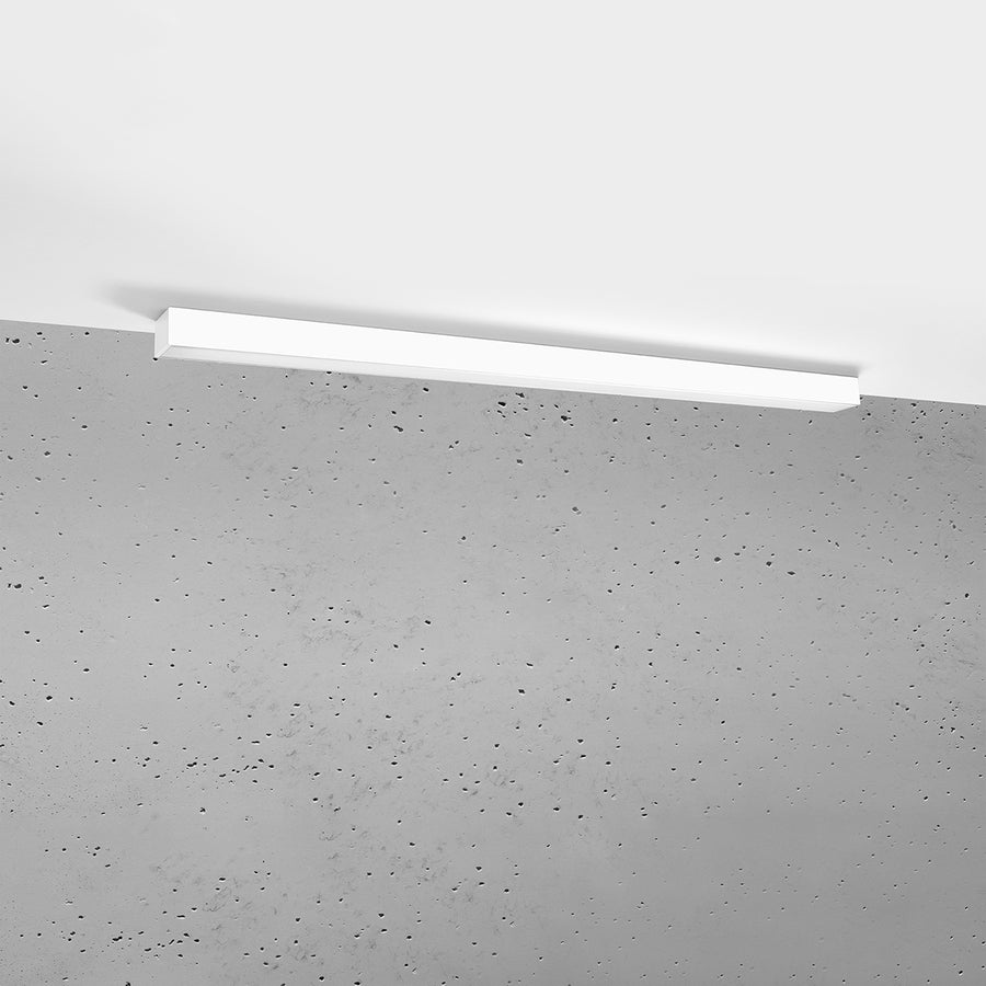 Plafonnier fixé au plafond blanc au-dessus d'un mur en béton brut.