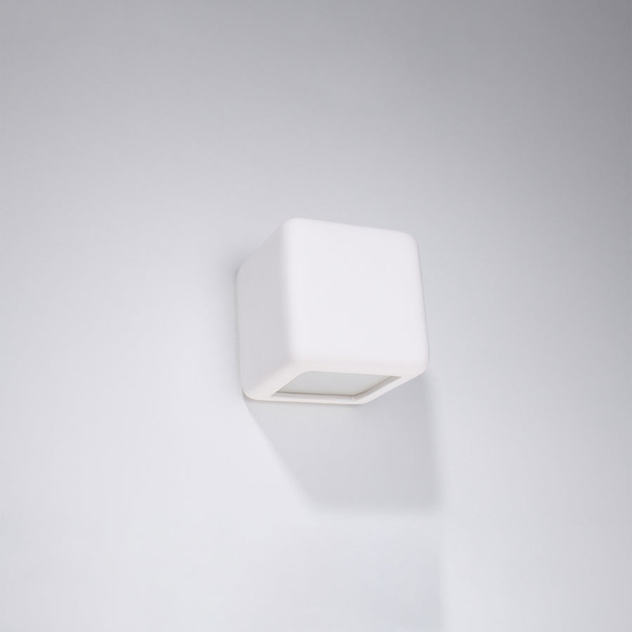 Applique cube blanche fixée sur un mur blanc, vue de face en légère plongée