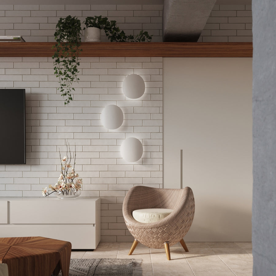 Mise en ambiance : trois appliques alignées sur mur de briques blanches dans un salon.
