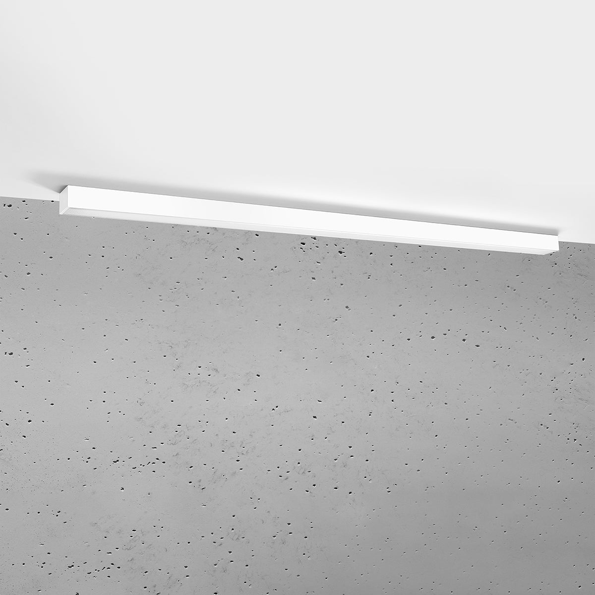 Plafonnier blanc fixé au plafond, mur en béton brut en arrière-plan.