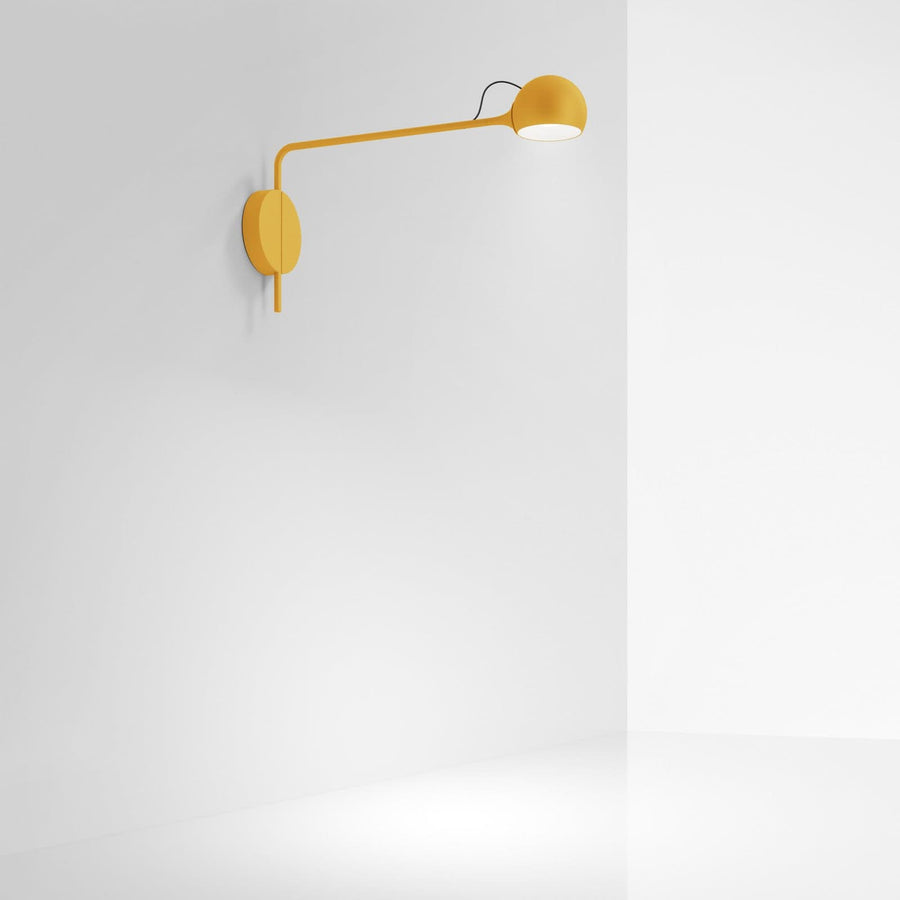 Applique murale jaune allumée sur mur blanc, halo lumineux diffus vers le bas