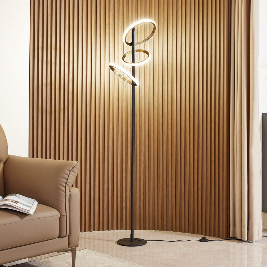 Lampadaire allumé devant un mur lambrissé, près d’un fauteuil, dans un salon.