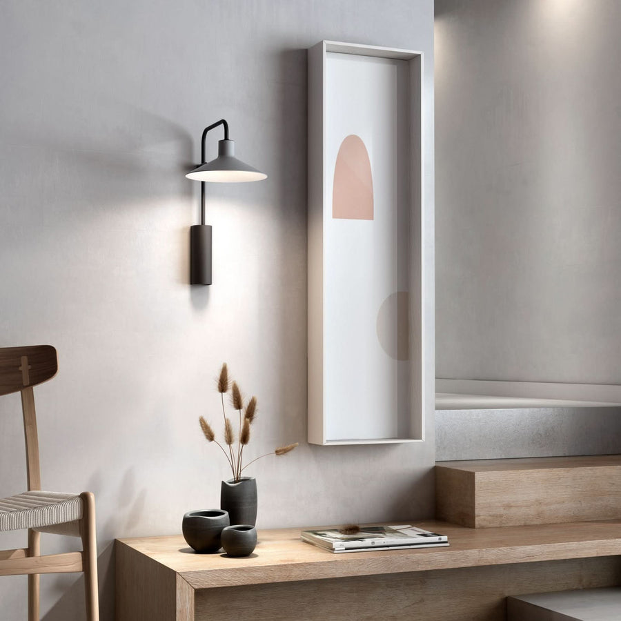 Vue en situation de l’applique au-dessus d’un meuble en bois et d’un cadre blanc