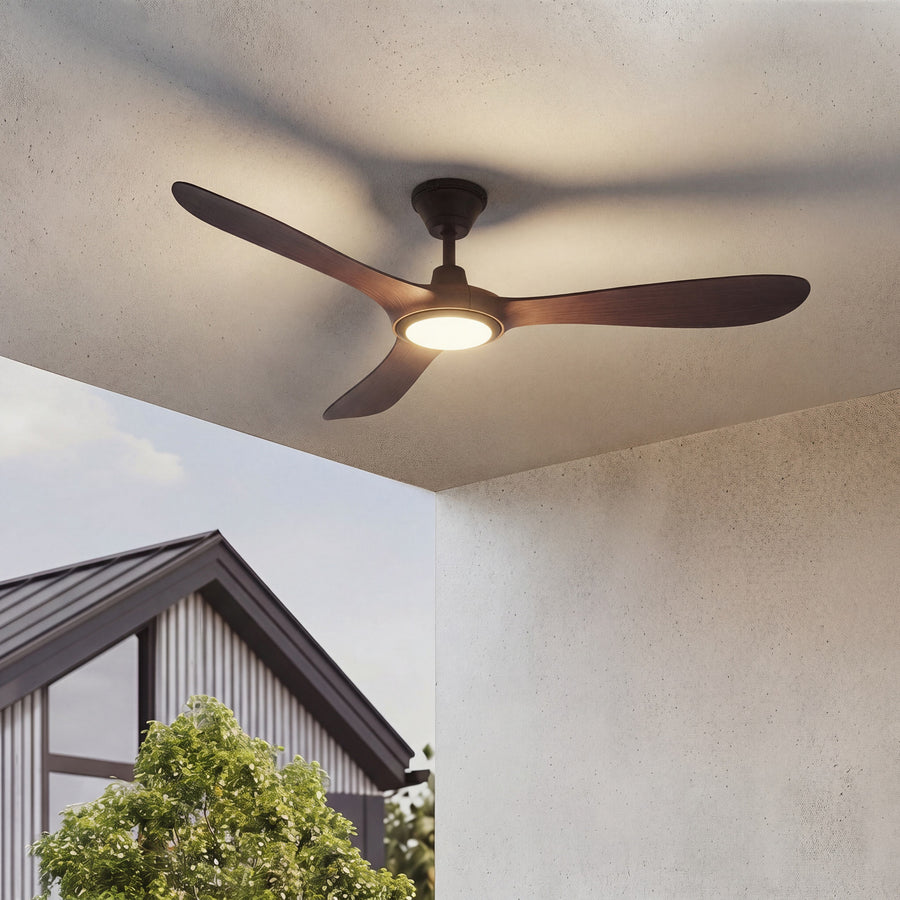 Ventilateur lumineux installé sous un auvent, pales noyer et lumière chaude allumée.
