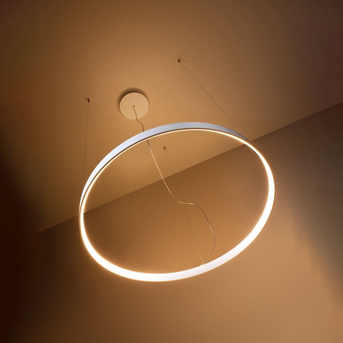 Anneau blanc allumé en éclairage chaud, vue en contre-plongée sous plafond beige