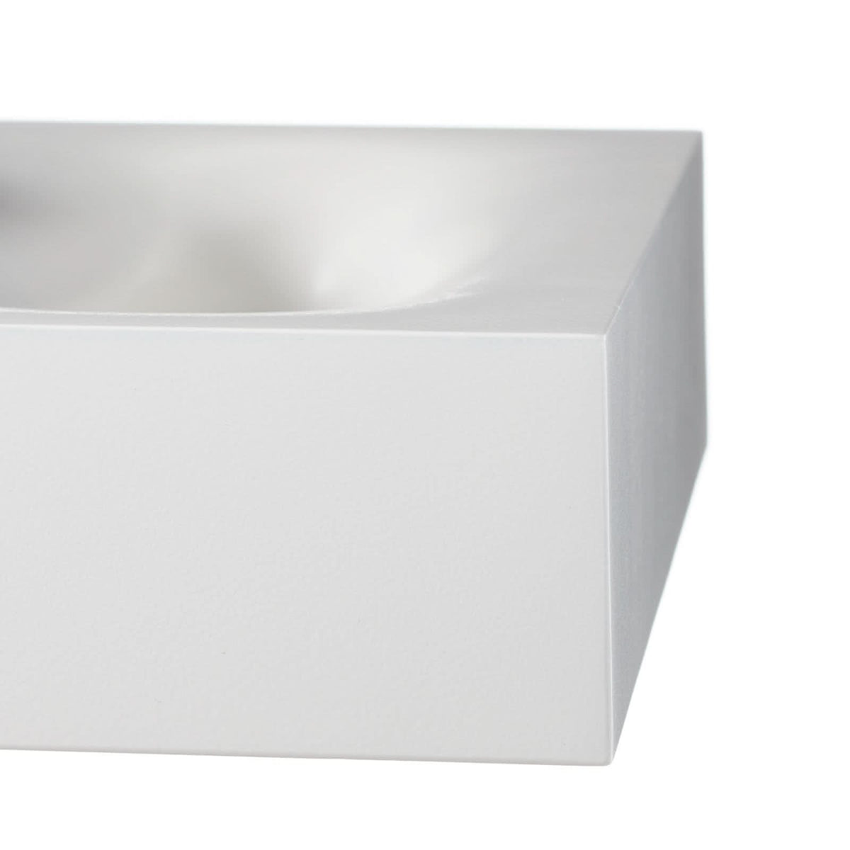 Gros plan sur l'angle arrondi et la finition mate blanche du luminaire.