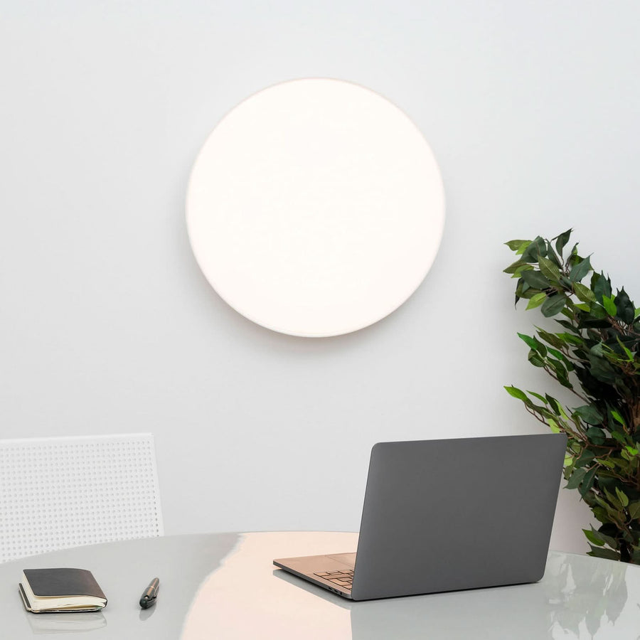 Applique murale LED ronde blanche au-dessus d'un bureau avec ordinateur portable.