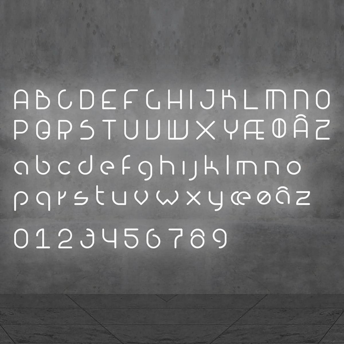 Alphabet complet lumineux en lettres blanches, chiffres inclus, présenté sur un mur béton.