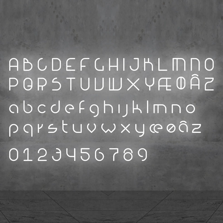 Alphabet complet lumineux en lettres blanches, chiffres inclus, présenté sur un mur béton.