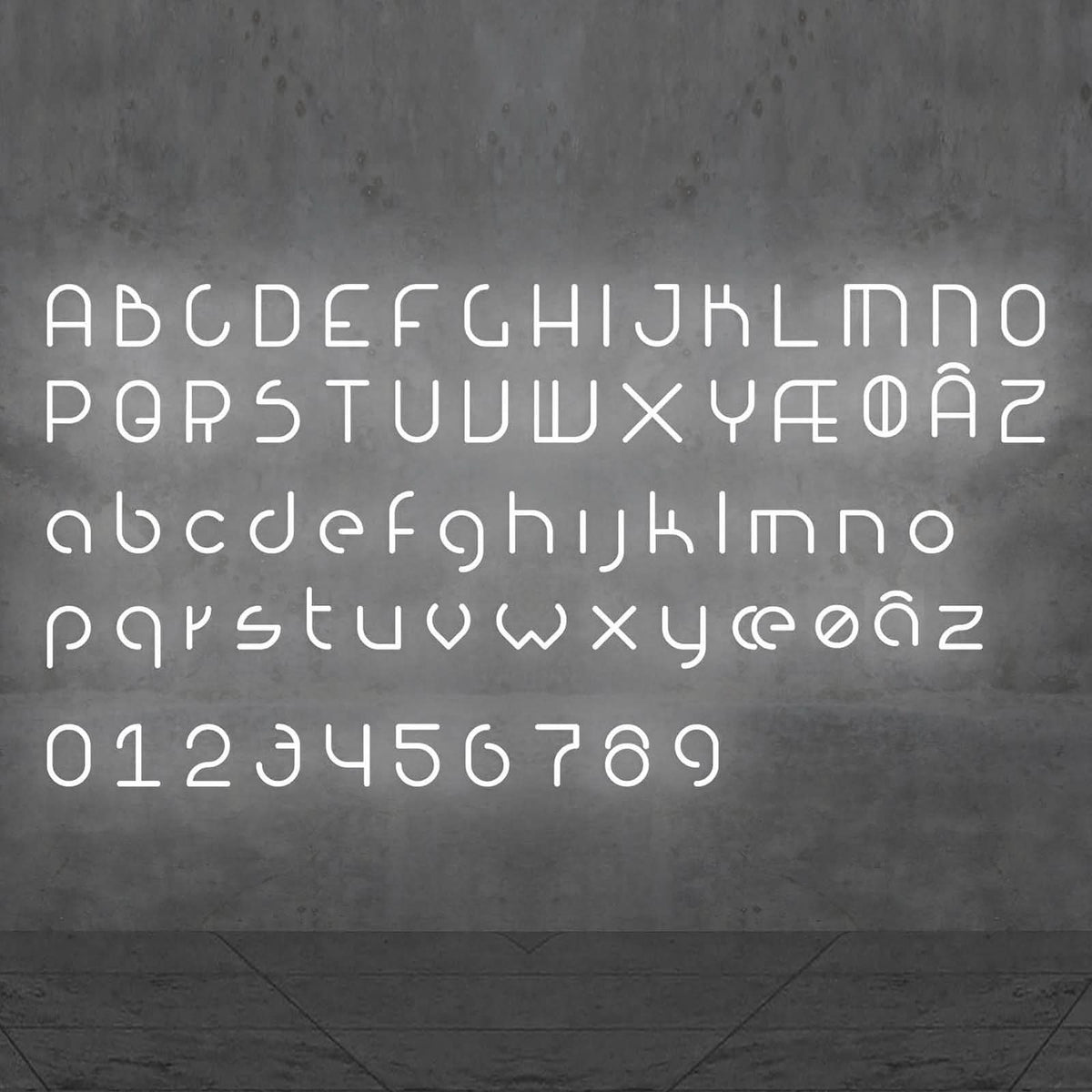 Vue de face de l'alphabet et des chiffres lumineux blancs sur un mur gris.