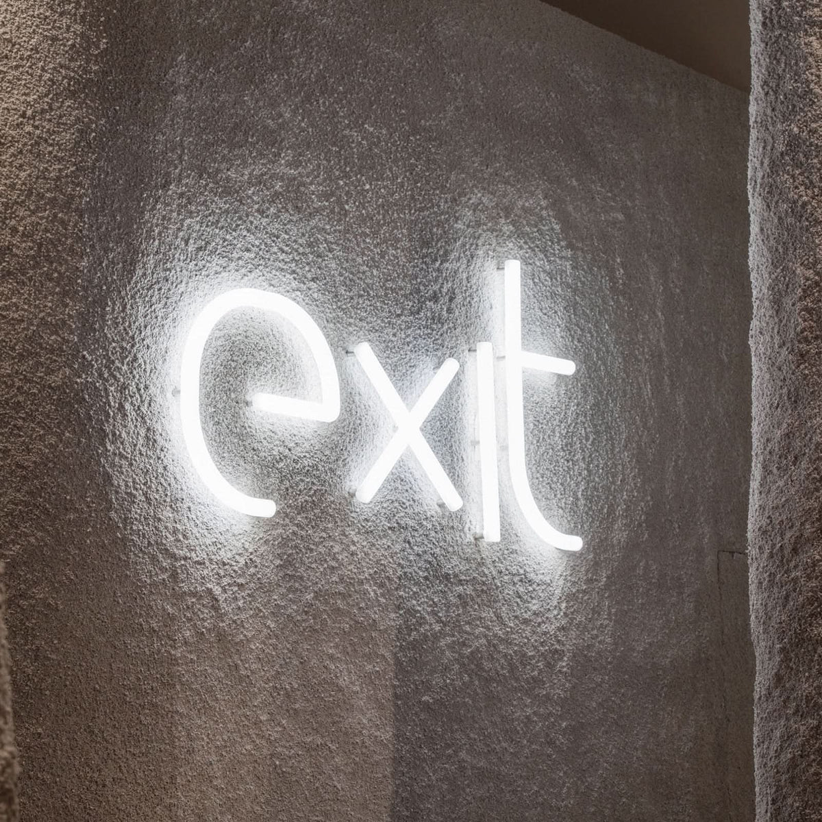 Détail du mot exit en lettres lumineuses sur un mur béton brut