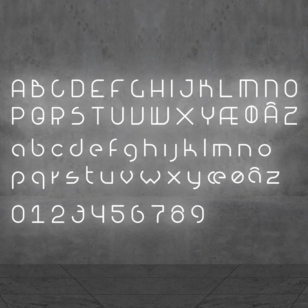 Alphabet complet, majuscules, minuscules et chiffres, affiché en lettres LED blanches sur un mur.